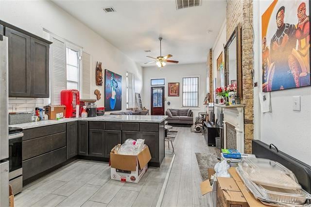 kitchen featuring tasteful backsplash, kitchen peninsula, light wood-type flooring, ceiling fan, and dark brown cabinetry