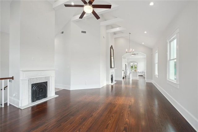 unfurnished living room with dark hardwood / wood-style floors, ceiling fan with notable chandelier, beam ceiling, a fireplace, and high vaulted ceiling