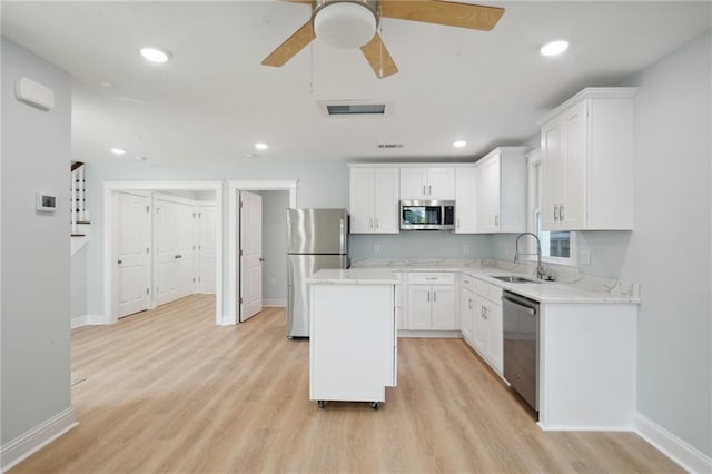 kitchen featuring appliances with stainless steel finishes, light hardwood / wood-style floors, white cabinets, ceiling fan, and sink