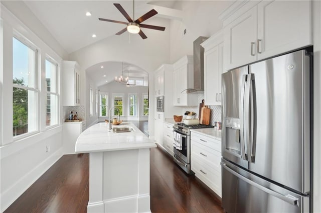 2412 N Rampart St, New Orleans, LA 70117 - kitchen featuring vaulted ceiling, wall chimney range hood, stainless steel appliances, ceiling fan with notable chandelier, and a sink