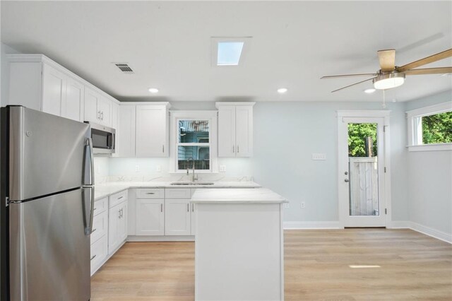 kitchen with appliances with stainless steel finishes, light hardwood / wood-style floors, white cabinetry, ceiling fan, and sink