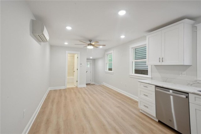 kitchen featuring dishwasher, a wall unit AC, white cabinets, light hardwood / wood-style flooring, and light stone countertops