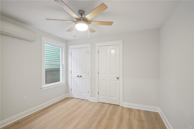 unfurnished bedroom featuring light wood-type flooring, ceiling fan, and a wall mounted air conditioner