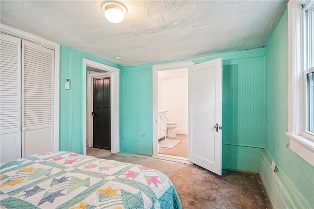 bedroom featuring concrete floors, ensuite bath, and a closet