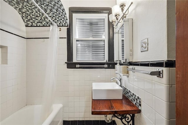 bathroom with shower / bath combination with curtain, tile walls, and sink