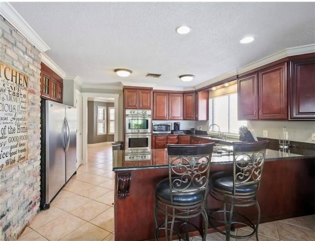 kitchen with a textured ceiling, light tile patterned flooring, sink, appliances with stainless steel finishes, and ornamental molding