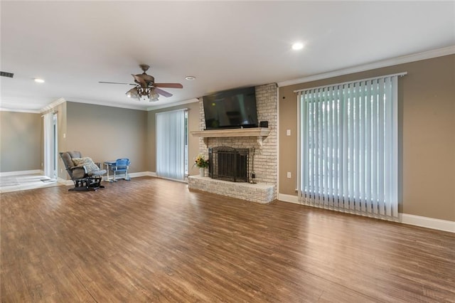 unfurnished living room with hardwood / wood-style flooring, crown molding, ceiling fan, and a brick fireplace