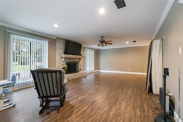 living room with a brick fireplace, hardwood / wood-style flooring, ornamental molding, and ceiling fan