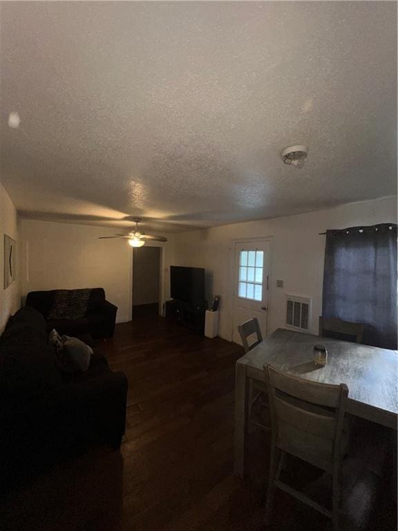 living room featuring a textured ceiling, wood-type flooring, and ceiling fan