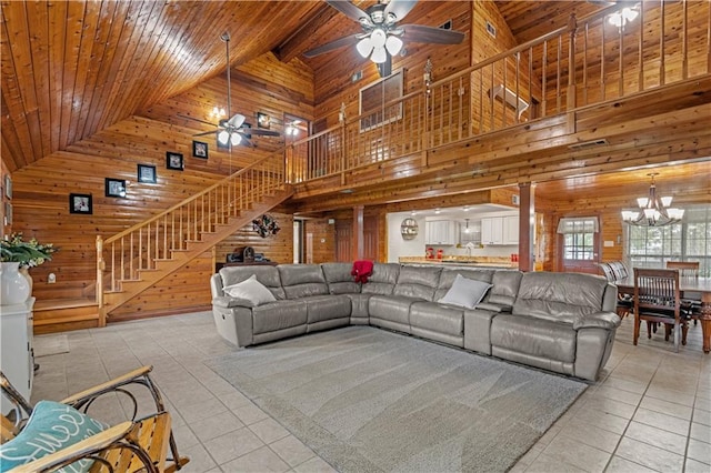 tiled living room with wood ceiling, high vaulted ceiling, ceiling fan with notable chandelier, wood walls, and ornate columns