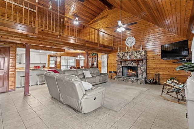 tiled living room with wood ceiling, ceiling fan with notable chandelier, wood walls, high vaulted ceiling, and a stone fireplace