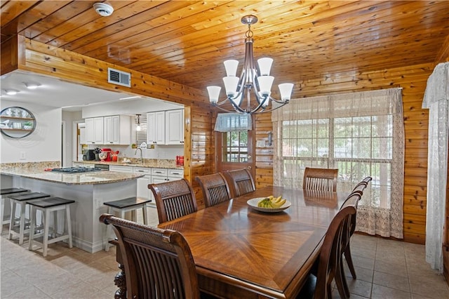 tiled dining room with wood ceiling, wooden walls, a chandelier, and sink