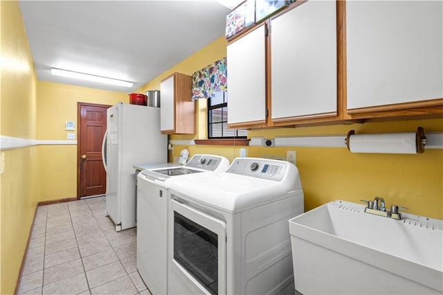 laundry area with washing machine and dryer, sink, light tile patterned floors, and cabinets