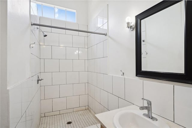 bathroom with tile walls, backsplash, vanity, and tiled shower