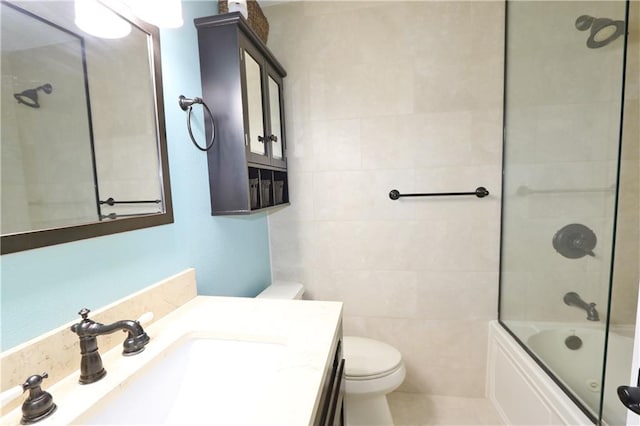 full bathroom with tile walls, tile patterned flooring, shower / bath combination with glass door, vanity, and toilet