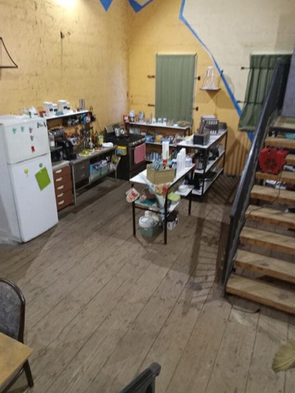 basement featuring hardwood / wood-style flooring and white fridge