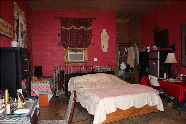 bedroom with cooling unit, dark wood-type flooring, and stainless steel refrigerator