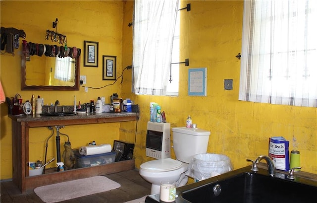 bathroom featuring heating unit, sink, a tub, and toilet