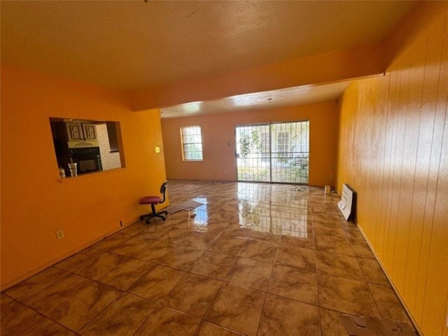 spare room featuring a fireplace and wood walls