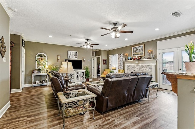 living room with a textured ceiling, dark hardwood / wood-style flooring, and a stone fireplace