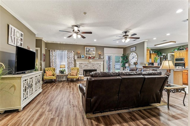 living room with hardwood / wood-style floors, a fireplace, ornamental molding, and a textured ceiling