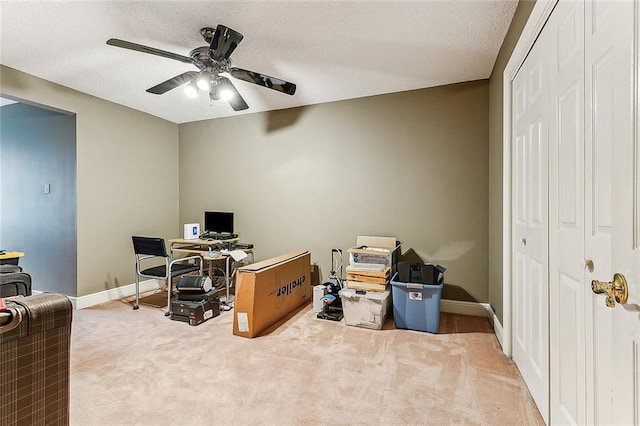 carpeted office space featuring ceiling fan and a textured ceiling