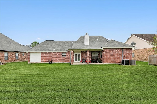 back of property featuring a garage, central air condition unit, and a yard