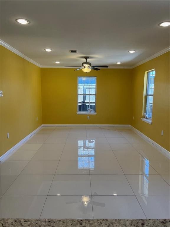 tiled empty room with ceiling fan and ornamental molding