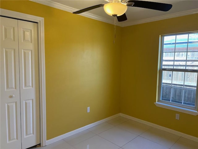 interior space featuring ceiling fan, light tile patterned flooring, a closet, and crown molding