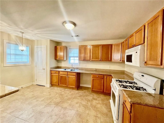 kitchen with hanging light fixtures, sink, white appliances, a chandelier, and light stone countertops