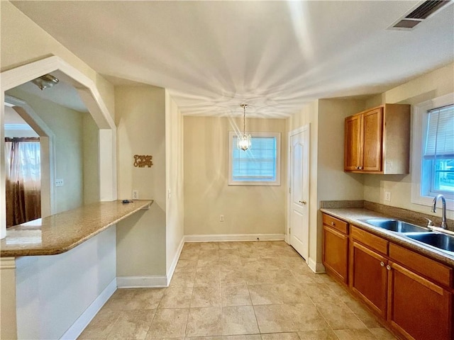 kitchen featuring light tile patterned floors, kitchen peninsula, sink, and pendant lighting