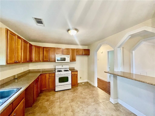 kitchen featuring white appliances, light tile patterned floors, and sink