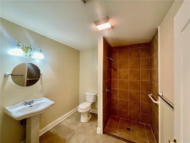 bathroom with a tile shower, tile patterned flooring, and toilet