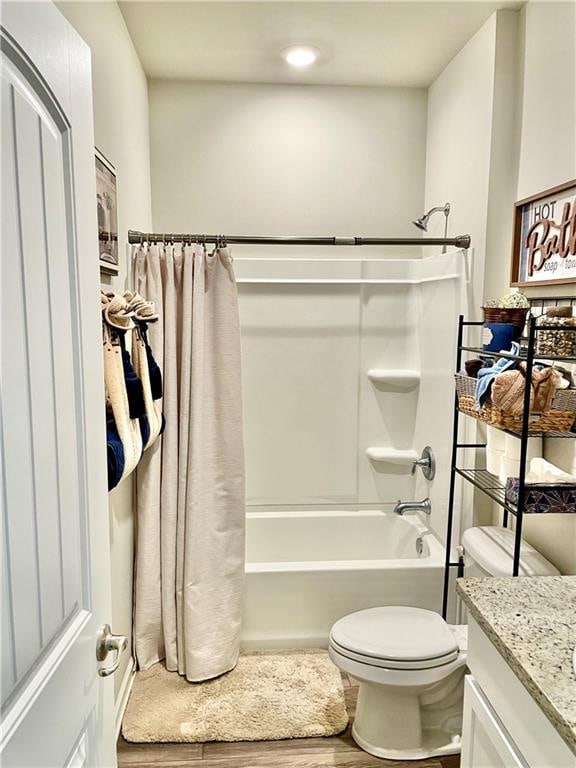 full bathroom with hardwood / wood-style floors, vanity, shower / tub combo with curtain, and toilet