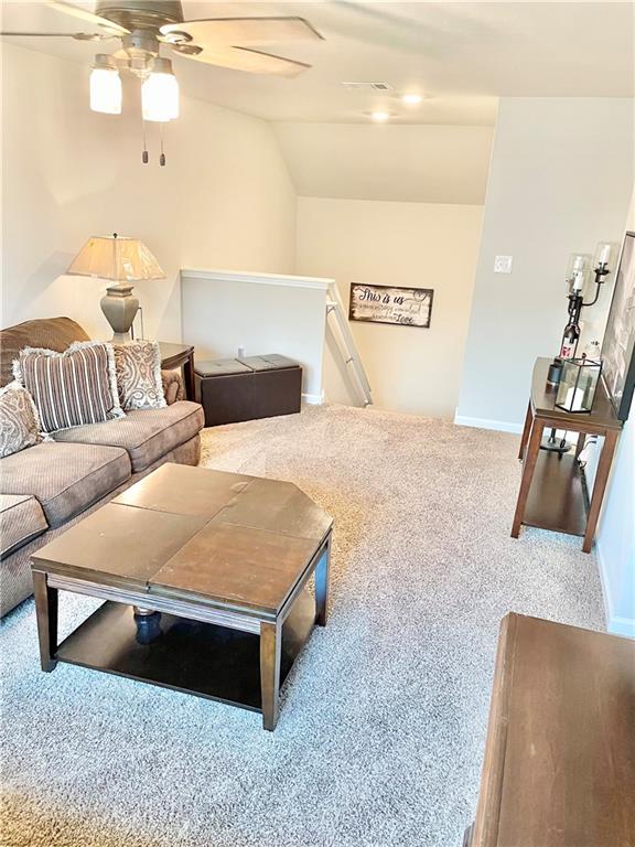 carpeted living room with ceiling fan and lofted ceiling