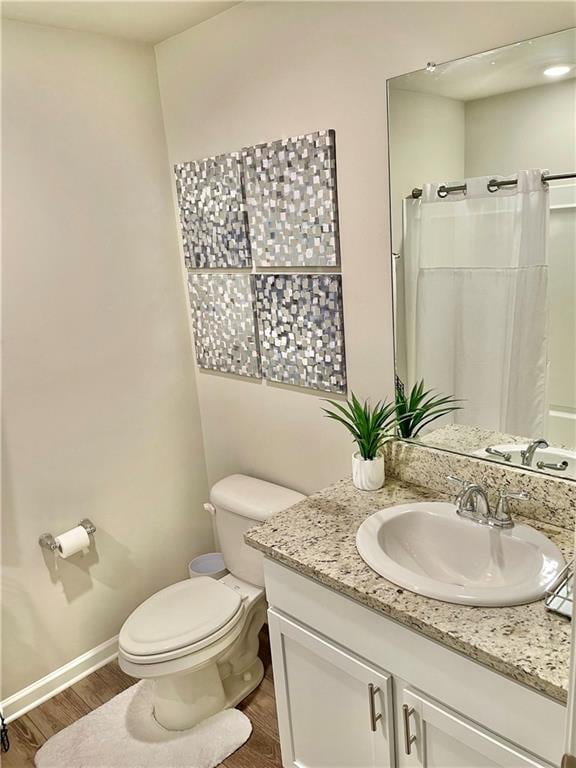 bathroom featuring curtained shower, toilet, vanity, and hardwood / wood-style flooring