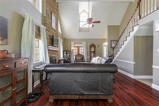 living room featuring ceiling fan, wood-type flooring, a fireplace, and high vaulted ceiling