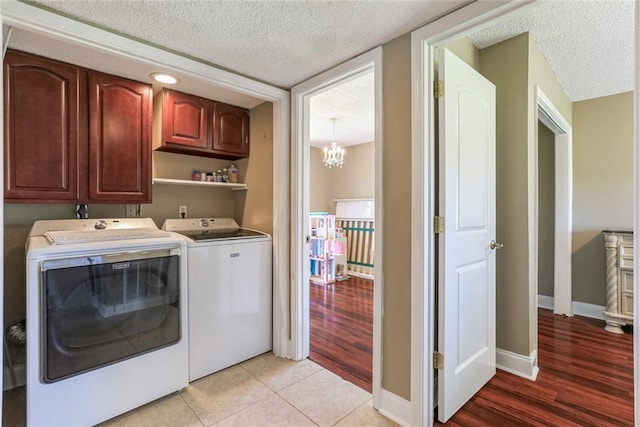 laundry area featuring a textured ceiling, light hardwood / wood-style flooring, a notable chandelier, and washing machine and dryer