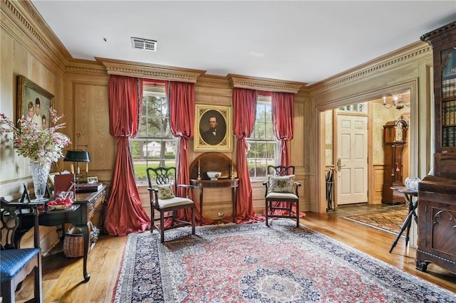 sitting room with a healthy amount of sunlight, wood-type flooring, and crown molding