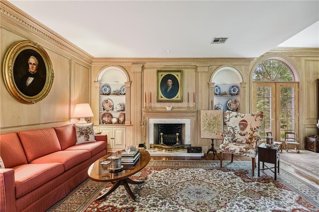 living room with built in features, a premium fireplace, and crown molding