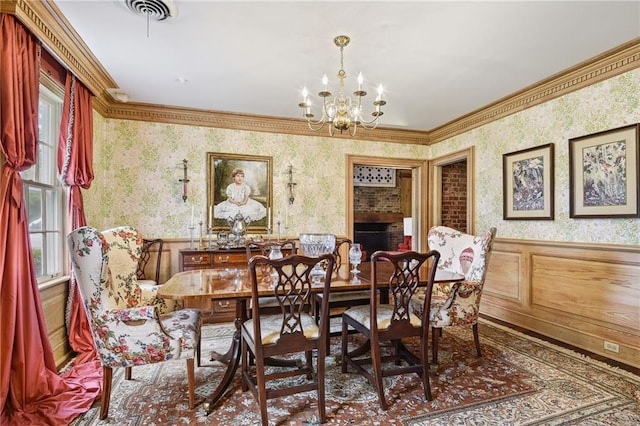 dining room with a fireplace, ornamental molding, and a chandelier