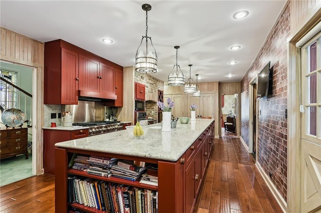 kitchen with light stone counters, a center island, dark hardwood / wood-style floors, and hanging light fixtures