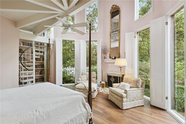 bedroom featuring ceiling fan, light hardwood / wood-style flooring, a high ceiling, and access to outside