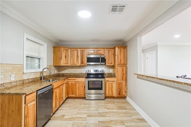 kitchen with appliances with stainless steel finishes, stone counters, sink, and crown molding