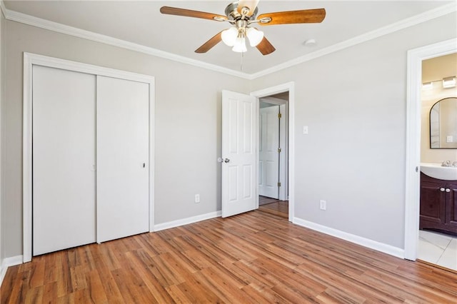 unfurnished bedroom with a closet, light hardwood / wood-style flooring, connected bathroom, and ornamental molding