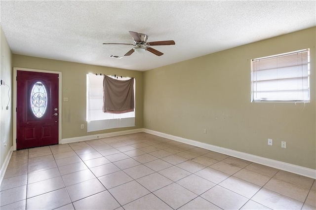 foyer with ceiling fan, plenty of natural light, light tile patterned floors, and a textured ceiling