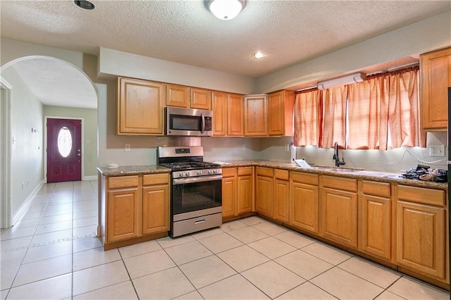 724042 Boston Dr, New Orleans, LA 70127 - kitchen featuring appliances with stainless steel finishes, arched walkways, a textured ceiling, a sink, and light tile patterned floors