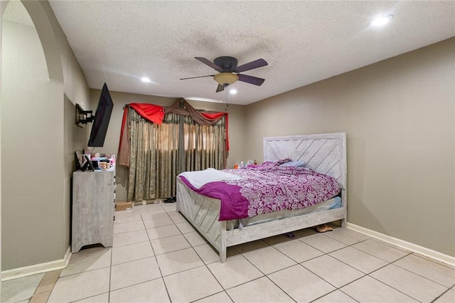 bedroom with ceiling fan, light tile patterned floors, and a textured ceiling