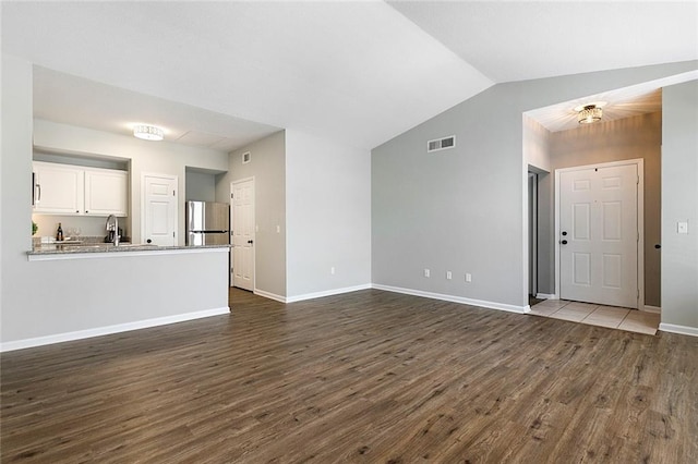 unfurnished living room with sink, dark wood-type flooring, and vaulted ceiling