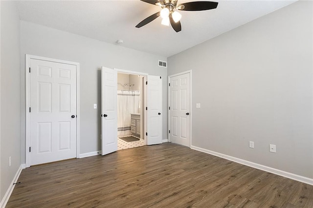 unfurnished bedroom featuring dark hardwood / wood-style floors, ensuite bath, and ceiling fan